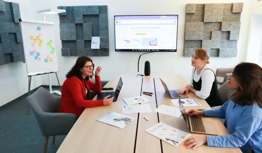 a group of people sitting around a table with laptops