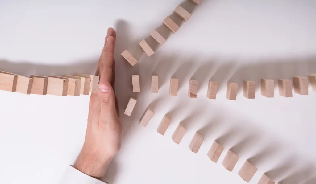A hand stopping a domino effect