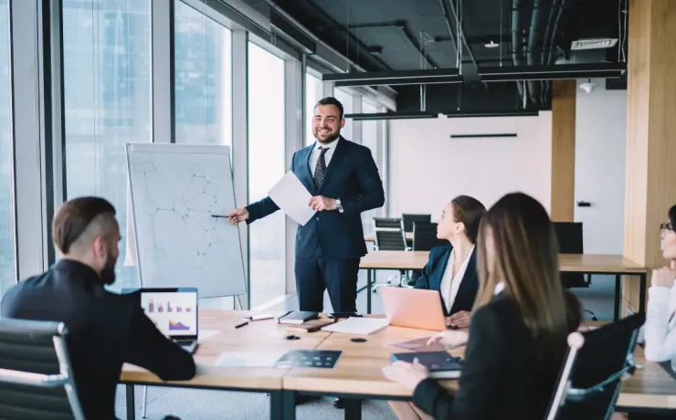 a person wearing a suit is presenting in front of a team