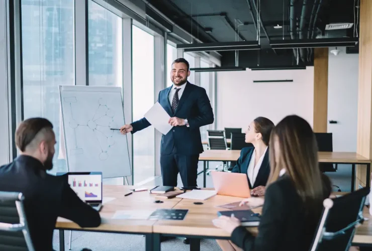 a person wearing a suit is presenting in front of a team