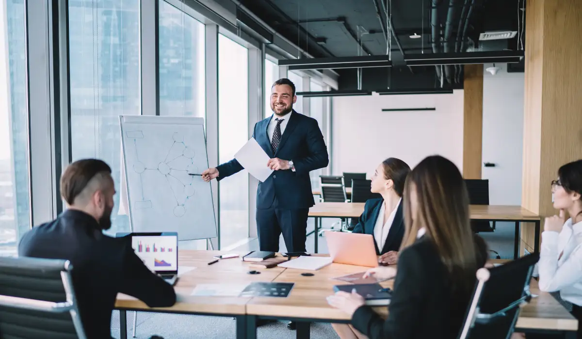 a person wearing a suit is presenting in front of a team
