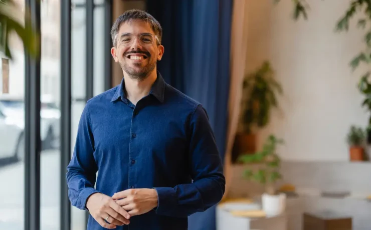 A startup founder wearing a blue shirt is smiling for the camera