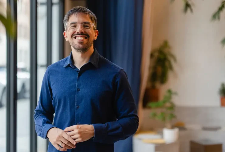 A startup founder wearing a blue shirt is smiling for the camera