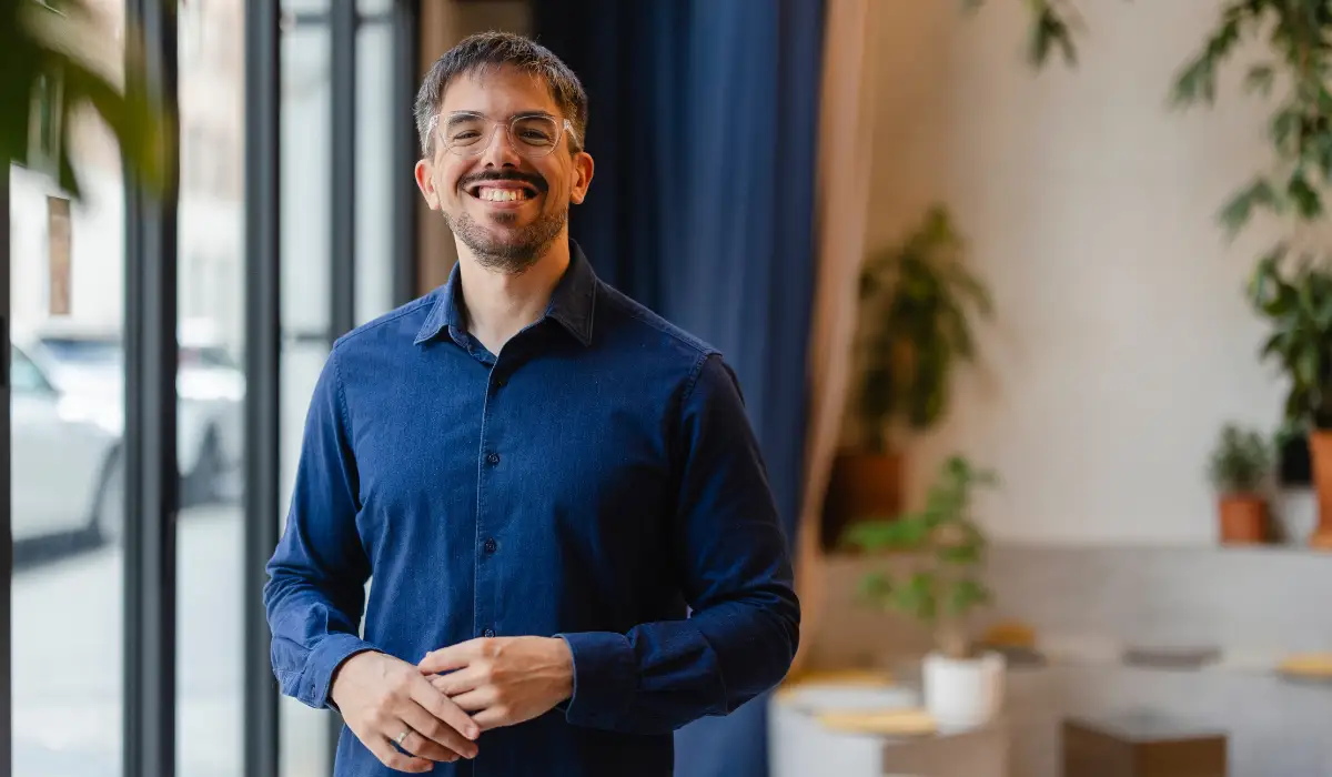 A startup founder wearing a blue shirt is smiling for the camera