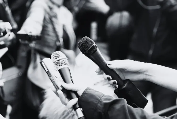 Multiple journalists holding mics.